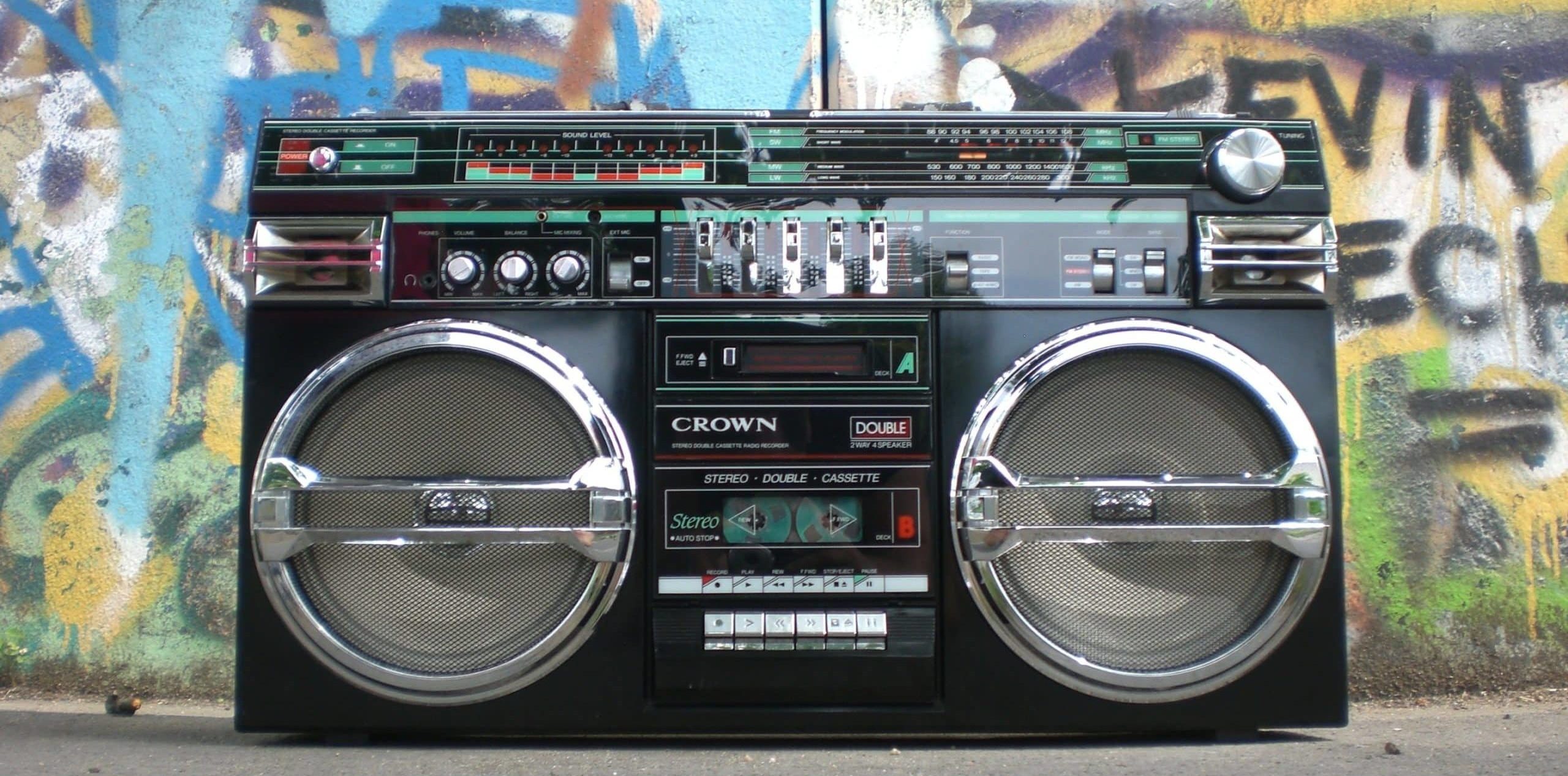 A boom box on the floor in front of a wall of graffiti art